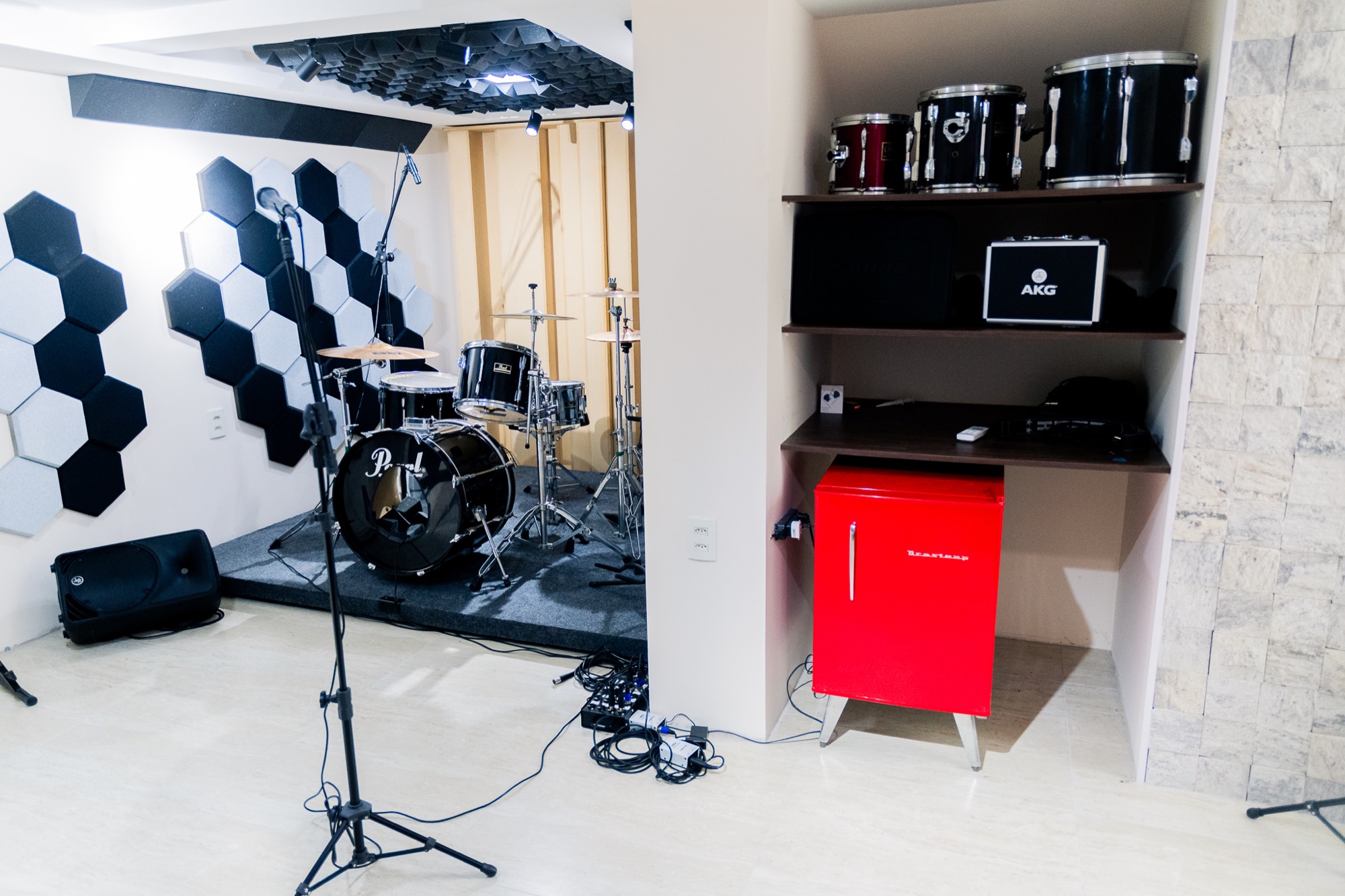 Novo ângulo da sala com bateria, microfones e detalhes do espaço